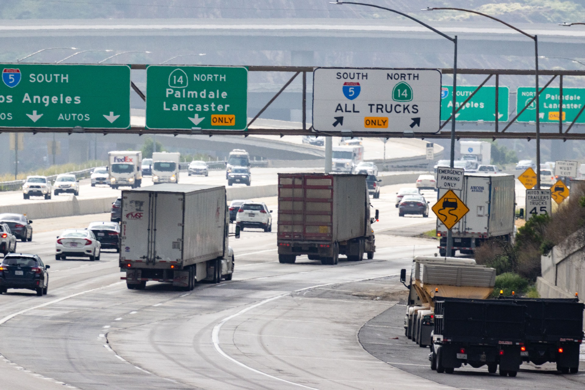 Los Angeles County Highway traffic with large trucks, overhead signs showing South and North lanes, and “All Trucks Only” restrictions.