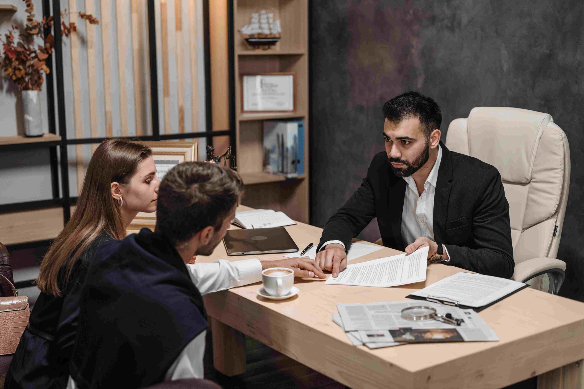 Business meeting in office: Attorney reviews documents with two clients around conference table.